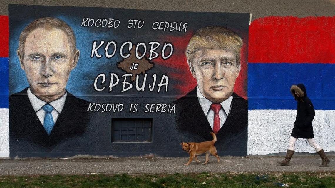 A woman passes by graffiti depicting the Russian President Vladimir Putin, left, and US President Elect Donald Trump in a suburb of Belgrade, Serbia, Tuesday, Dec. 6, 2016.