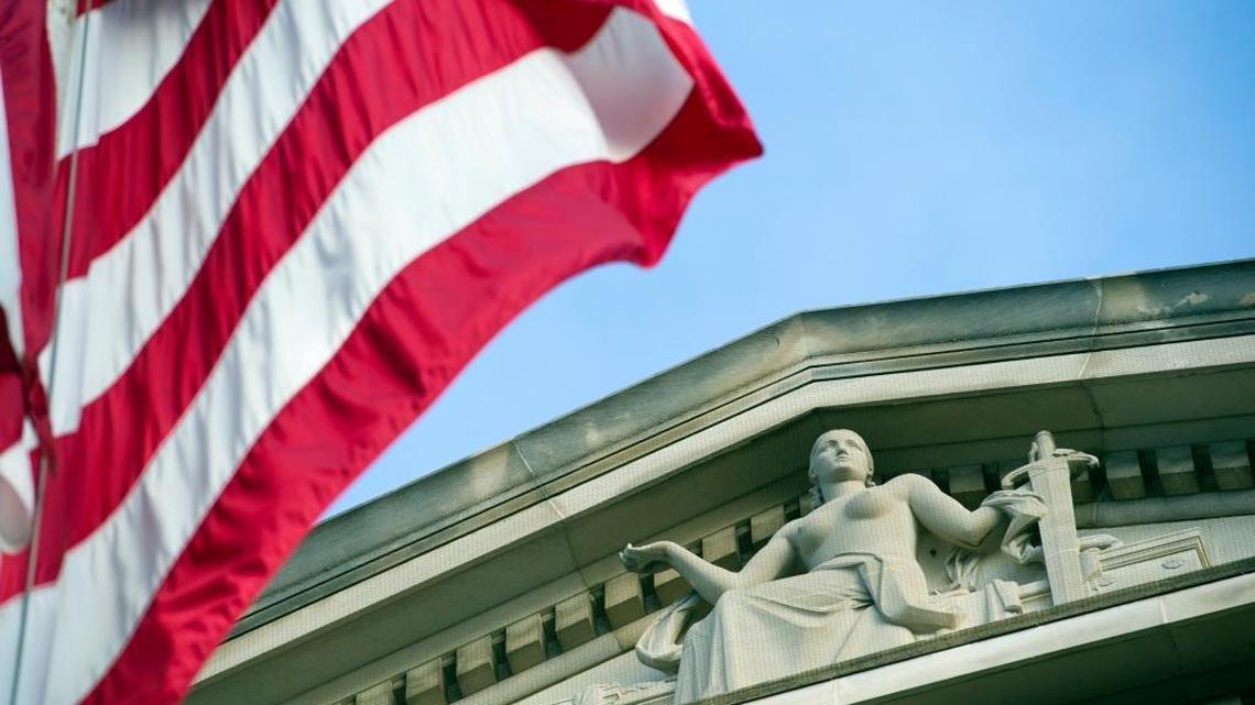 The American flag flies outside the Justice Department, where inquiries into controversies involving Hillary Clinton could become delicate matters whether she or Donald Trump becomes the president.