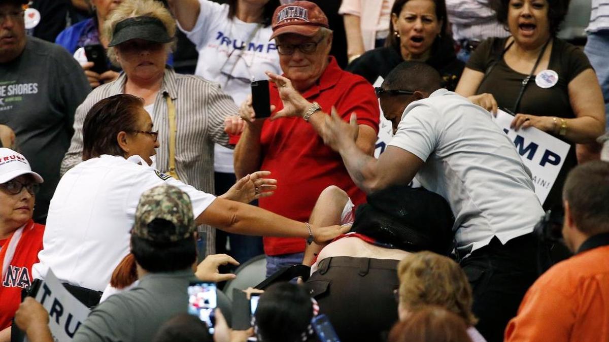 A supporter of Republican presidential candidate Donald Trump, right, scuffles with an anti-Trump protester, as security, left, intervenes before Trump spoke at a campaign rally March 19, 2016, in Tucson, Ariz.