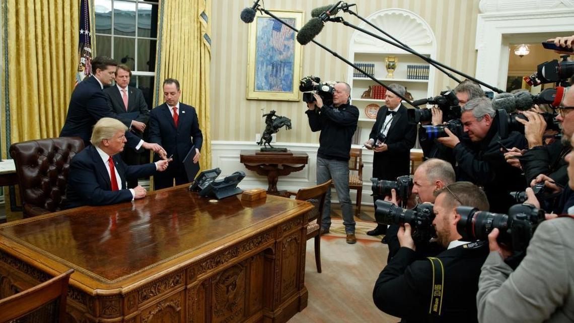 In this Jan. 20, 2017, photo, President Donald Trump hands over his pen after signing his first executive order in the Oval Office of the White House in Washington. Itâ€™s the first full work week for the Trump administration, and the talk is all about emoluments, executive orders, a border tax, TPP and much more.