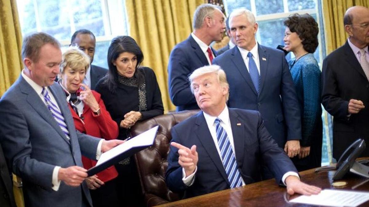 President Donald Trump looks over towards Budget Director Mick Mulvaney, left, after signing an executive order in the Oval Office of the White House in Washington, March 13, 2017