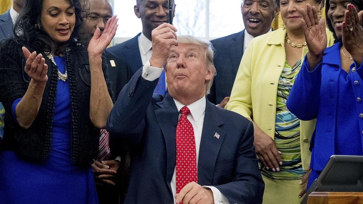 President Donald Trump holds up his pen after signing the Historically Black Colleges and Universities HBCU Executive Order, Tuesday, Feb. 28, 2017, in the Oval Office in the White House in Washington.