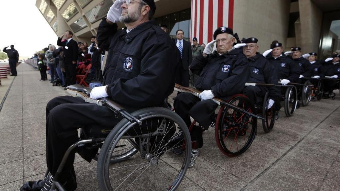 John Fay, left, leads a line of fellow honor guards from the Lone Star Chapter of the Paralyzed Veterans of American during the Pledge of Allegiance before a Veterans Day parade in downtown Dallas on Nov. 11, 2014.