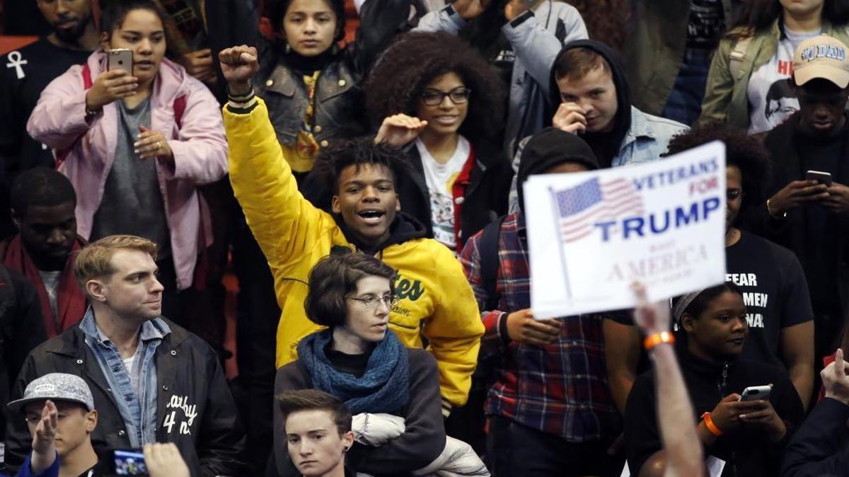 A protester raises his fist to supporters of Republican presidential candidate Donald Trump before a rally on the campus of the University of Illinois-Chicago on Friday, March 11, 2016. The rally was postponed because of safety concerns.