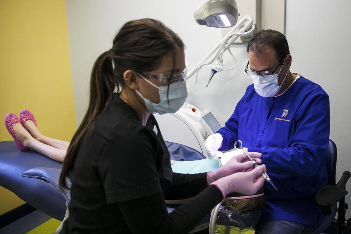 Jonathan Shenkin, right, a pediatric dentist, works on a patient at his offices in Augusta, Maine.