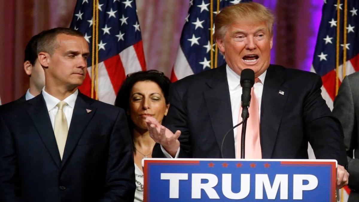 In this March 15, 2016, photo, Donald Trump's campaign manager, Corey Lewandowski, listens at left as Trump speaks in Palm Beach, Fla.