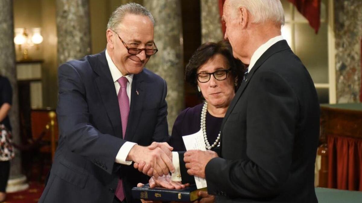 Vice President Joe Biden shakes hands with Senate Minority Leader Sen. Chuck Schumer, D-N.Y., accompanied by Schumer’s wife, Iris Weinshall, during a a mock swearing-in ceremony. Schumer will lead an effort to dilute Republican efforts to repeal Obamacare.