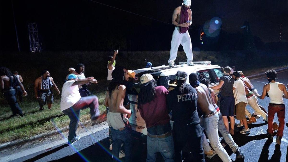 Protesters surround a police vehicle on Old Concord Road in Charlotte, N.C., on Tuesday night. A protest began on Old Concord Road at Bonnie Lane, where a Charlotte-Mecklenburg police officer had fatally shot a man in the parking lot of The Village at College Downs apartment complex Tuesday afternoon. The man who died was identified late Tuesday as Keith Scott, 43, and the officer who fired the fatal shot was CMPD Officer Brentley Vinson.
