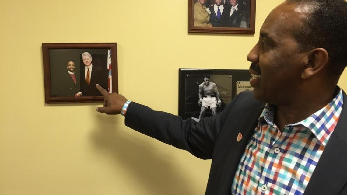 Bishop Wayne T. Jackson of Great Faith Ministries International will host Republican presidential nominee Donald Trump at his predominantly black church on Saturday, Sept. 3, 2016, in Detroit as Trump looks to court African-American voters. Jackson points to a picture on his office wall of himself with former President Bill Clinton on Friday, Sept. 2, 2016.