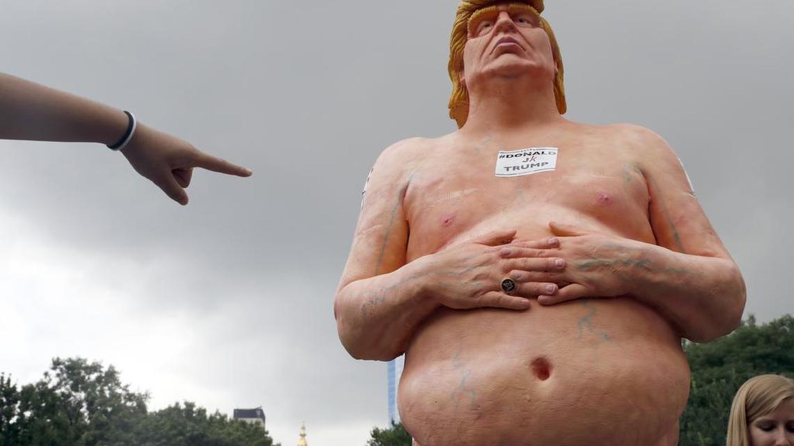 A woman points at a statue of a naked Republican presidential candidate Donald Trump, Thursday, Aug. 18, 2016 in New York's Union Square. The statue was removed by New York City Department of Parks & Recreation employees.