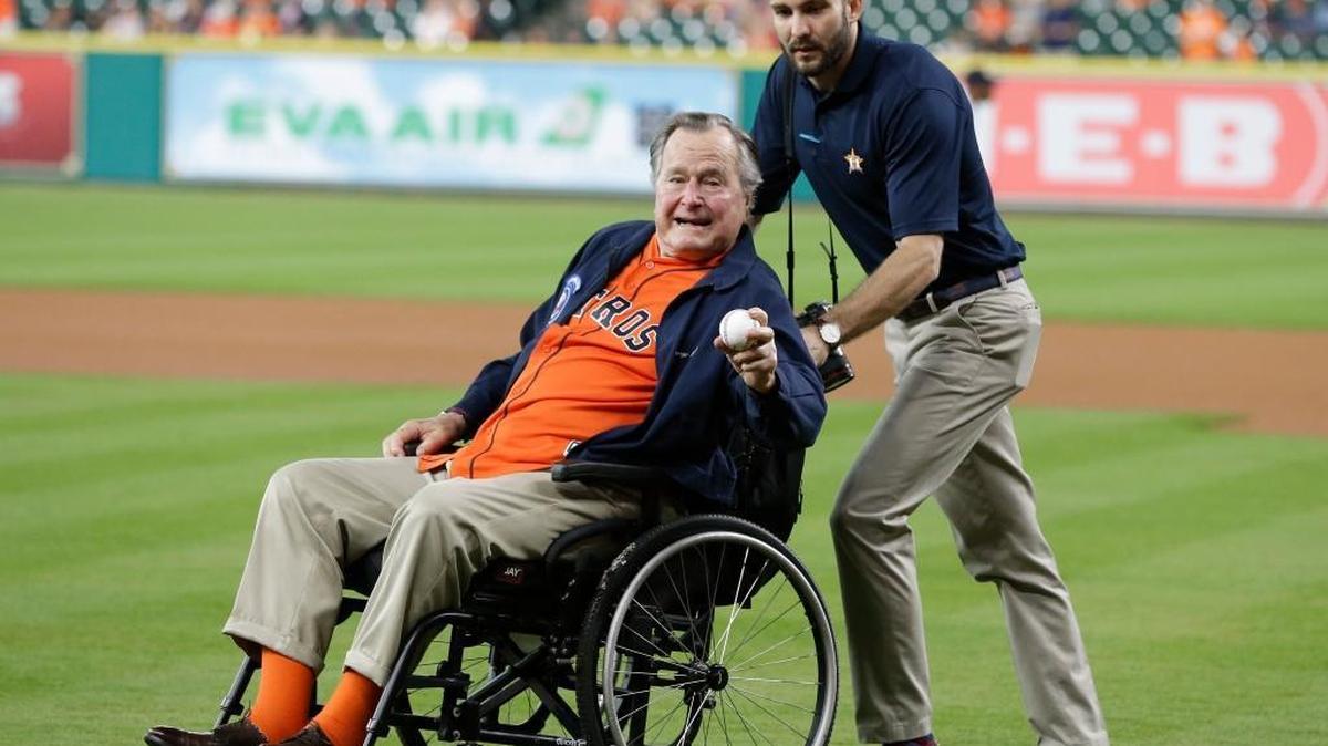 In this April 12, 2016, file photo, former President George H.W. Bush shows his pitching grip as he is wheeled to the field to throw out the ceremonial first pitch to Houston Astros starting pitcher Collin McHugh before the baseball game against the Kansas City Royals in Houston.