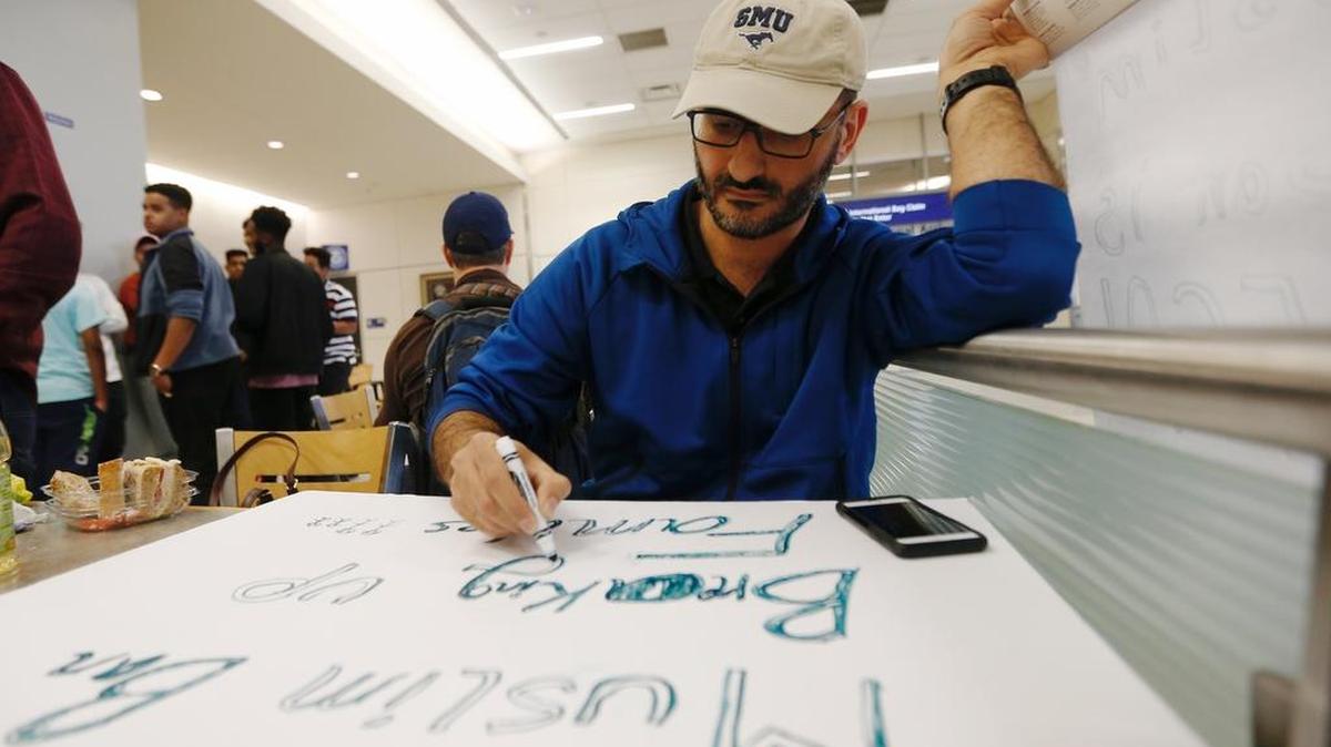 Al Alzubi creates a sign to protest President Donald Trump's executive order banning muslims from certain middle eastern countries at Terminal D at DFW airport, Saturday, Jan. 28, 2017. Alzubi is friends with international students at SMU whose Syrian parents are being detained at the airport.