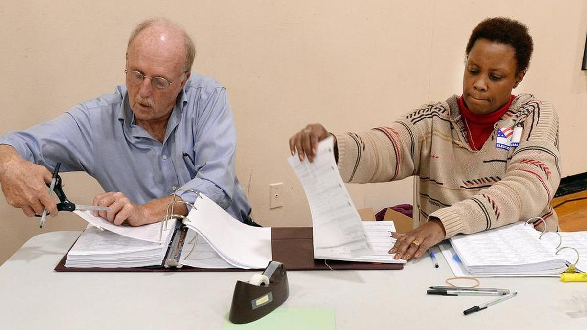Tom Clark, assistant judge and Kem Gilmore work as a team to get forms to voters the old fashioned way at E.K. Powe Elementary School voting precinct in Durham, N.C. Tuesday, Nov.8, 2016. A computer glitch shut down the county's new electronic voting system causing some delays at some precincts.