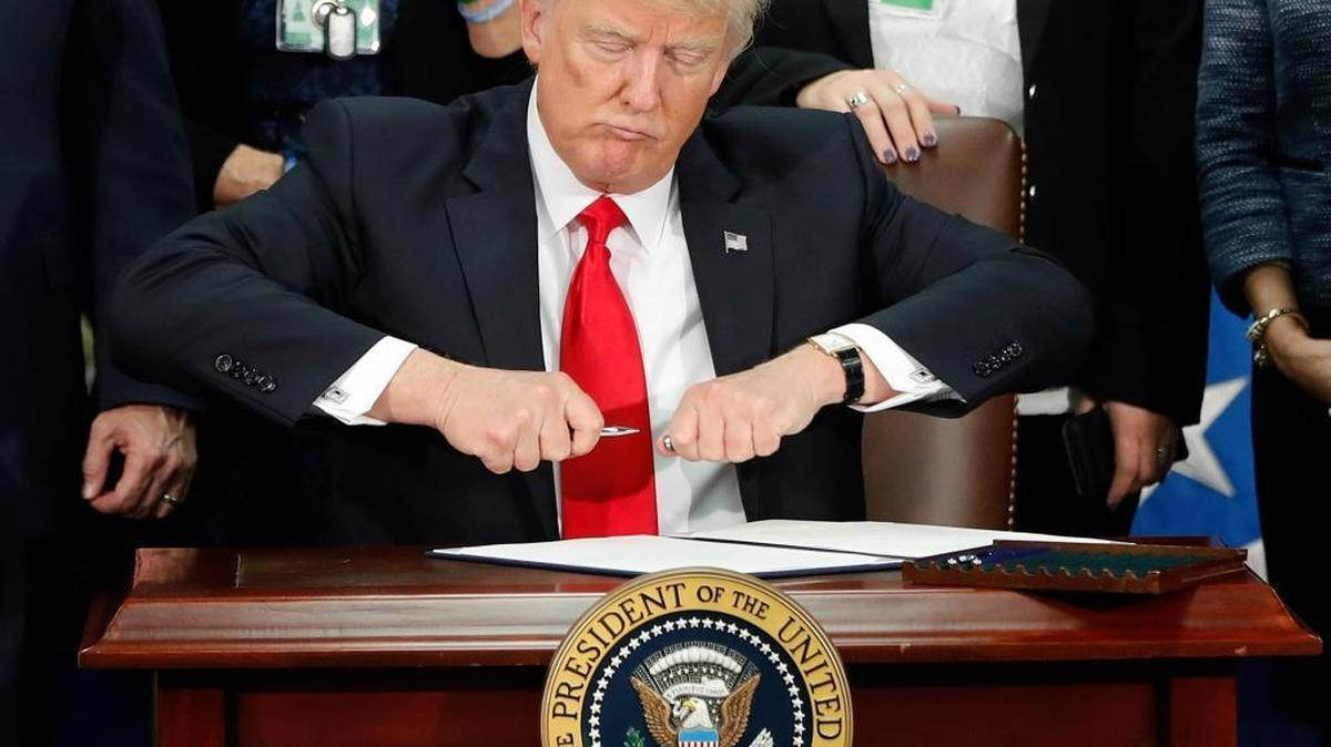 In this Jan. 25, 2017, file photo, President Donald Trump uncaps a pen to sign an executive order for immigration actions to build a border wall during a visit to the Homeland Security Department in Washington.