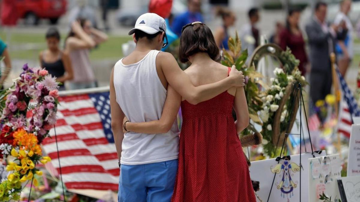 A couple spend a quiet moment at a makeshift memorial honoring the victims of the Pulse nightclub mass shooting Monday, June 20, 2016, in Orlando, Fla.
