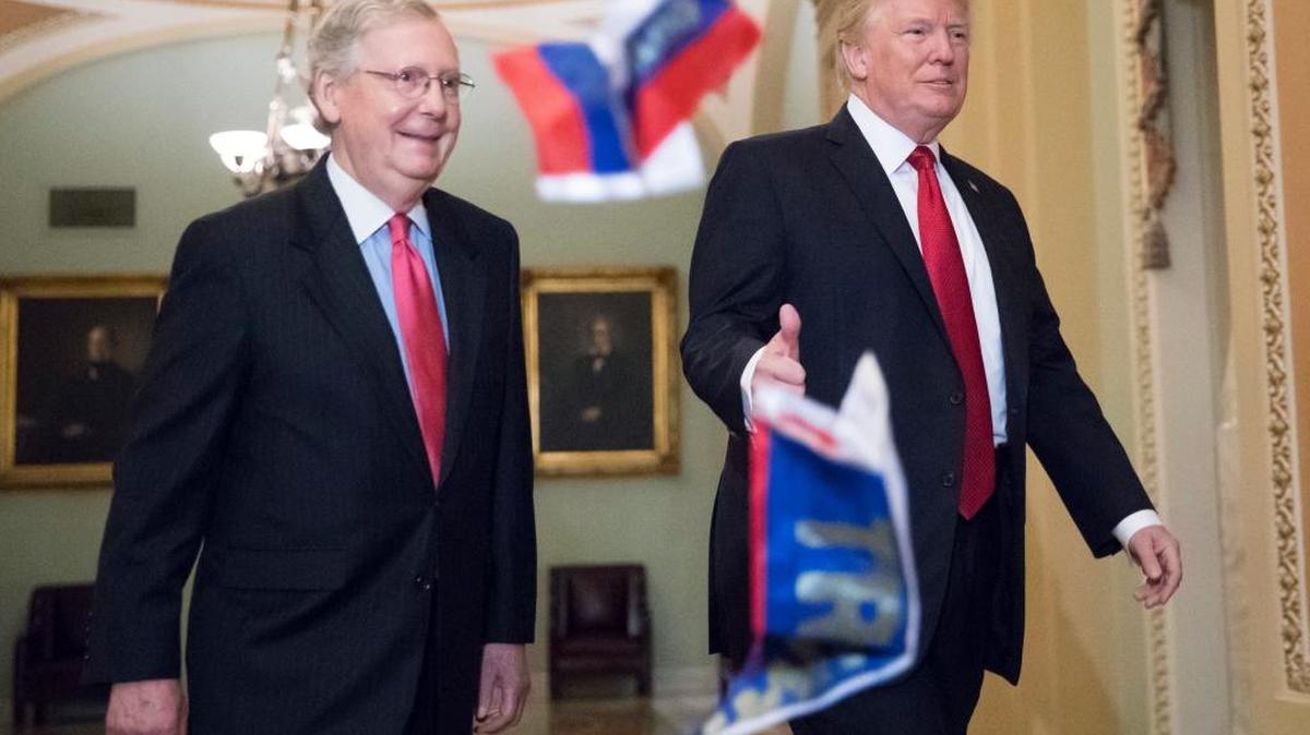 Small Russian flags bearing the word "Trump" are thrown by a protester toward President Donald Trump, as he walks with Senate Majority Leader Mitch McConnell, R-Ky., on Capitol Hill to have lunch with Senate Republicans.