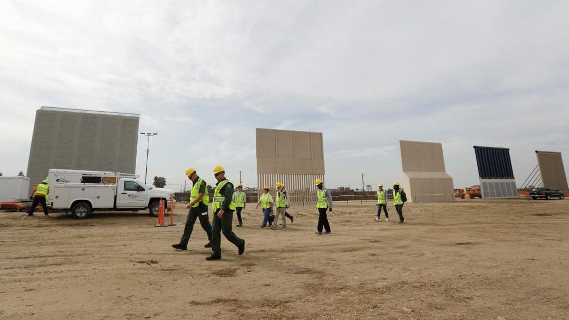 People pass border wall prototypes as they stand near the border with Tijuana, Mexico in San Diego.