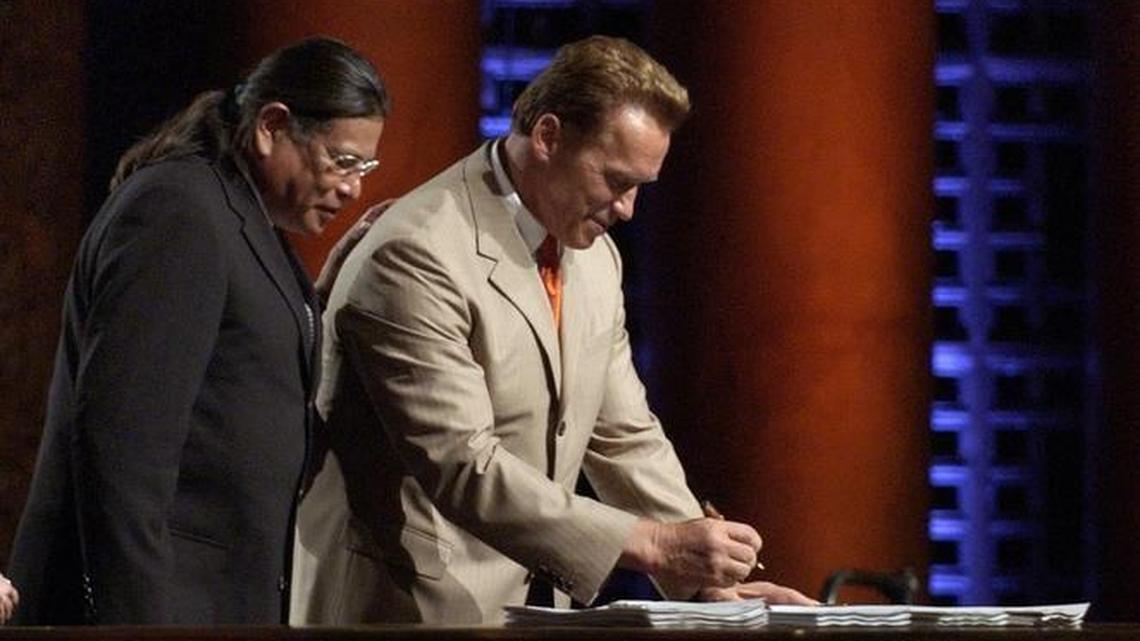 Anthony Pico, of the Viejas band of Kumeyaay Indians, puts his hand on the back of Gov. Arnold Schwarzenegger's as he watches the governor sign the first of five renegotiated gaming compacts with Indian tribes in California on June 21, 2004.