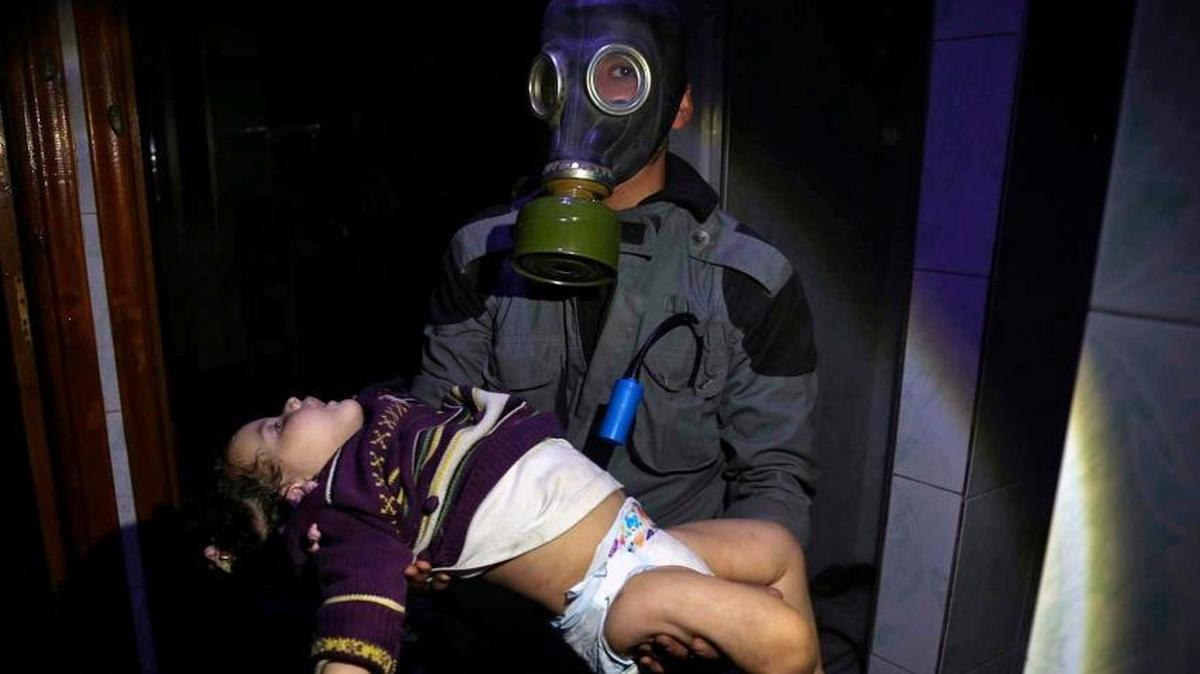 This April. 8, 2018 image released by the Syrian Civil Defense White Helmets, shows a rescue worker carrying a child following an alleged chemical weapons attack in the rebel-held town of Douma, near Damascus, Syria.