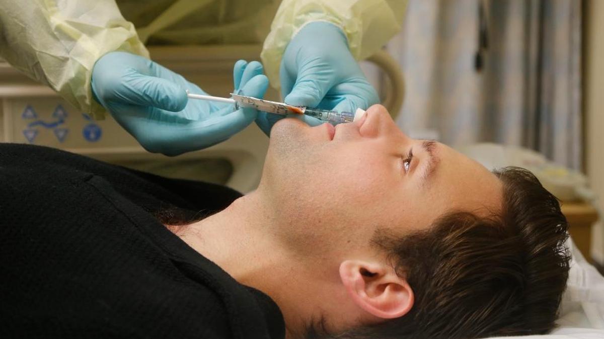 In this Jan. 14, 2014, photo, Daniel Bennett, 26, of College Park, Md., has live flu virus sprayed into his nose as part of a study at the National Institutes of Health in Bethesda, Md.