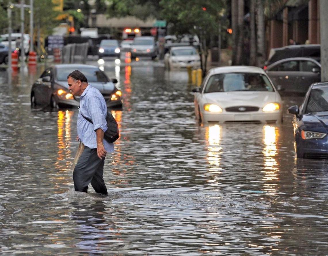 Pedestrians make their way through the flooded streets in the Brickell area of Miami on Aug. 1. Property owners in Miami-Dade, Broward and Palm Beach counties account of 16.5 percent of all flood insurance policies across the country.