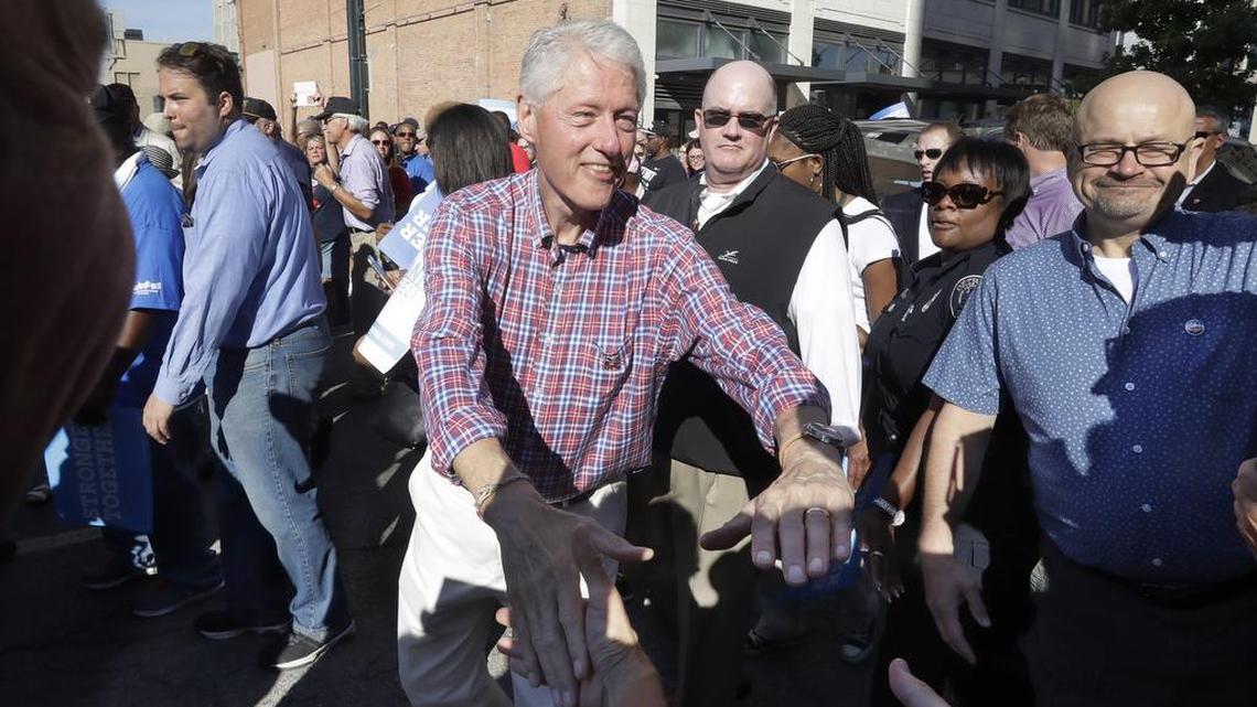 Former President Bill Clinton shakes hands as he marches with union members in the annual Labor Day parade, Monday, Sept. 5, 2016 in Detroit. Clinton earned nearly $18 million over five years as honorary chancellor of a for-profit university.
