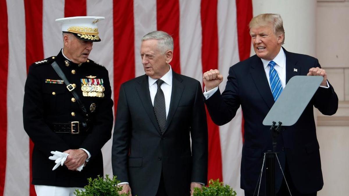 President Donald Trump, right, gestures while on stage with Joint Chiefs Chairman Gen. Joseph Dunford, left, and Defense Secretary Jim Mattis, center, at the Memorial Amphitheater in Arlington National Cemetery in Arlington, Va., on May 29, during a Memorial Day ceremony.