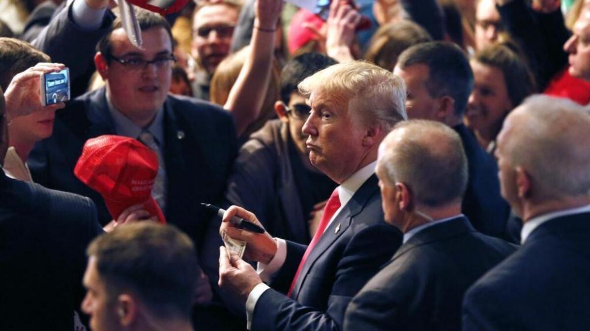 Republican presidential candidate Donald Trump looks down the row of supporters before signing an autograph on a dollar bill during a rally at the Milwaukee Theatre on Monday, April 4, 2016, in Milwaukee.