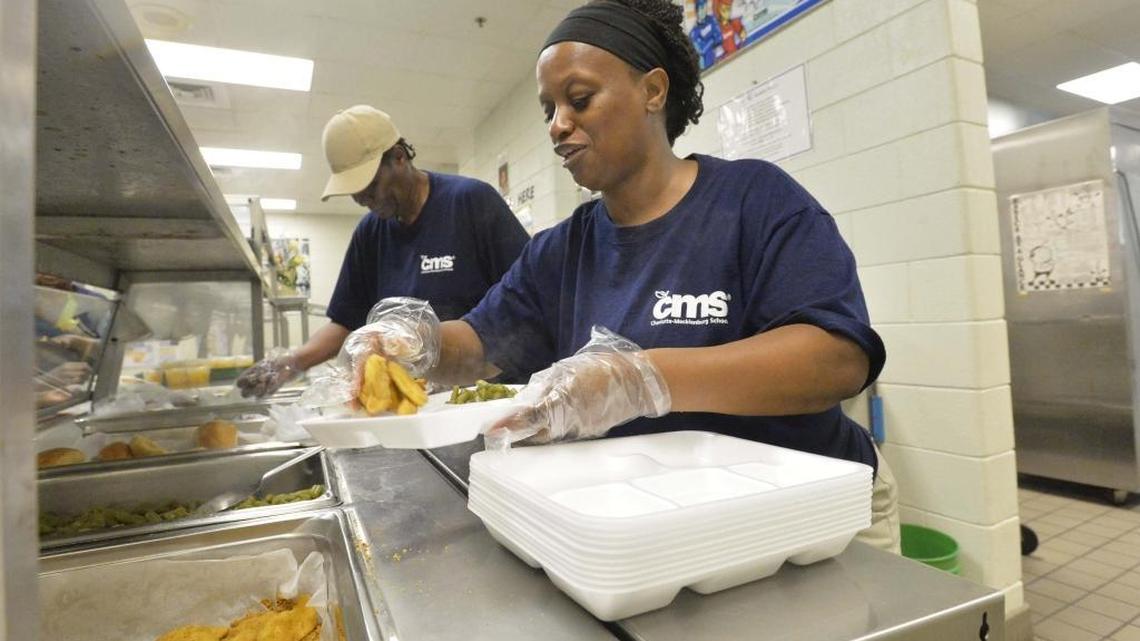 Charlotte-Mecklenburg Schools cafeteria employees Judy Jefferson (left) and Trina Steele dish out green beans and chicken nuggets for children during lunch at Barringer Academic Center on Tuesday, June 17, 2014.