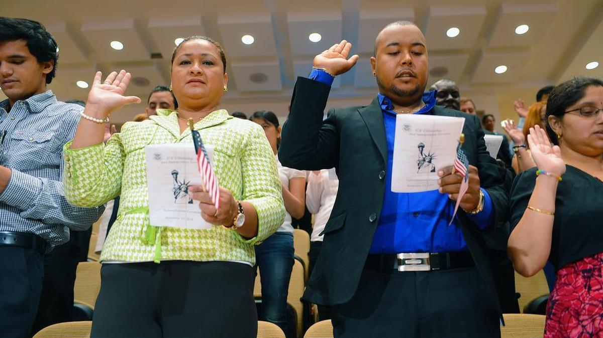 In this file photo, Luisa Judith Mejia (green shirt), from Honduras and Osiel Rodriguez (blue shirt) from Mexico raise their right hand as they take the oath of American citizenship in Charlotte, NC.