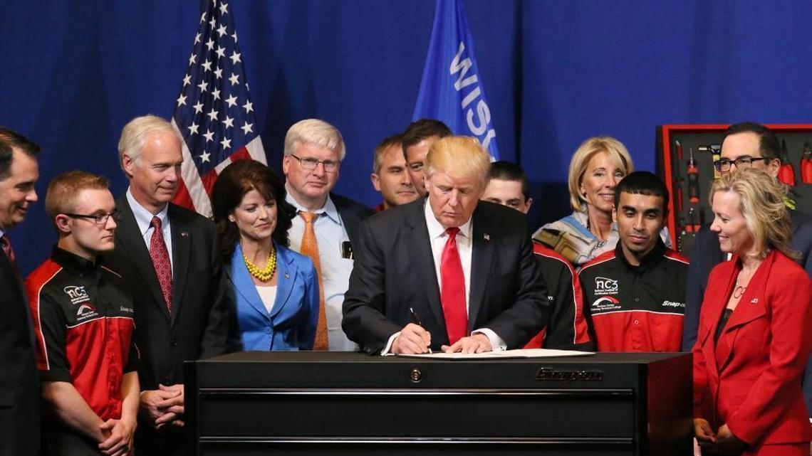 Surrounded by Snap-on workers and executives, President Donald Trump celebrates with them after signing a workplace executive order on Tuesday, April 18, 2017, at the Snap-on Inc. headquarters in Kenosha, Wis.