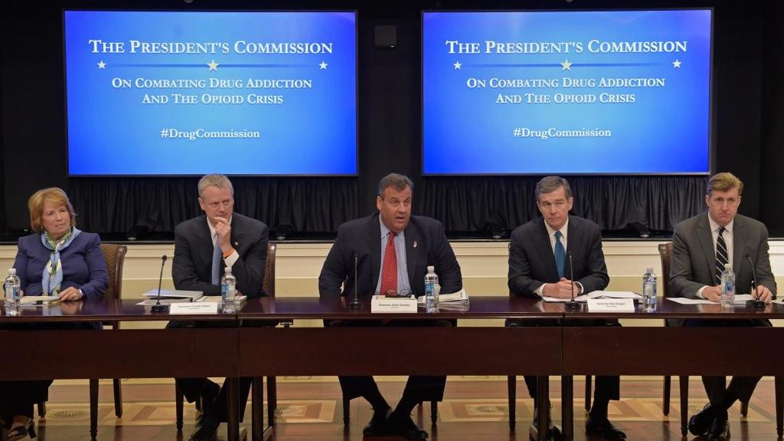 New Jersey Gov. Chris Christie, center, chairman of the President's Commission on Combating Drug Addiction and the Opioid Crisis, peaks at the beginning of the first meeting of the commission on combating drug addiction and the opioid crisis, Friday, June 16, 2017, in the Eisenhower Executive Office Building at the White House complex in Washington. From left are , Dr. Bertha K. Madras, a Harvard Medical School professor who specializes in addiction biology, Massachusetts Gov. Charlie Baker, Christie, North Carolina Gov. Roy Cooper, and former Rhode Island Rep. Patrick Kennedy.