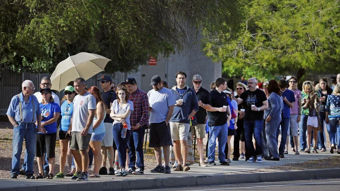 People wait in line to vote in the Arizona Presidential Primary Election in Phoenix, Ariz.