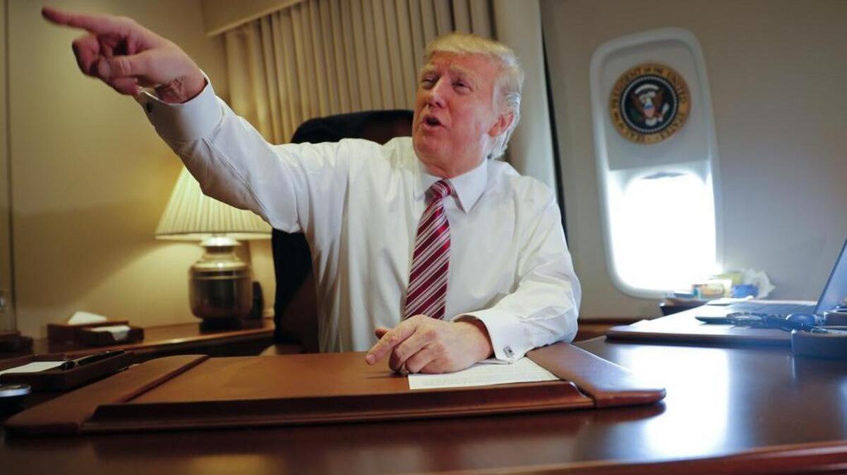 President Donald Trump points towards members of the media while seated at his desk on Air Force One upon his arrival at Andrews Air Force Base, Md.