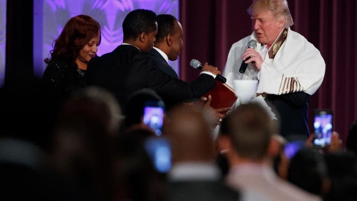 Republican presidential candidate Donald Trump wears a prayer shawl as he is presented with a gift during a church service at Great Faith Ministries, Saturday, Sept. 3, 2016, in Detroit.