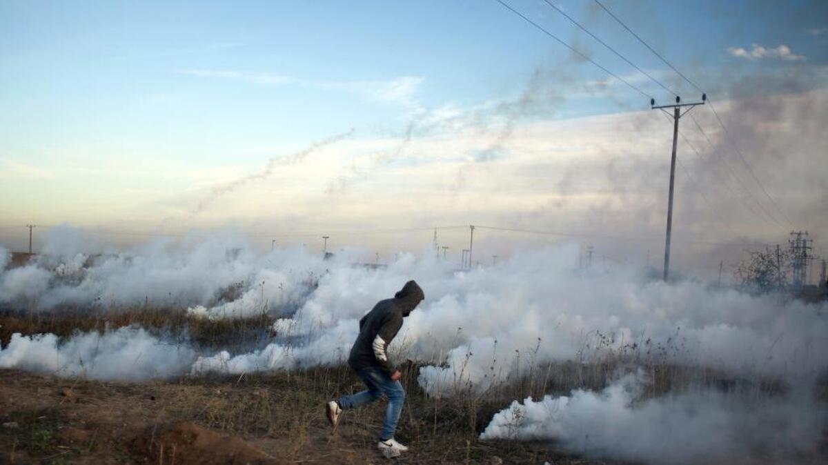 Palestinian protesters run for cover during clashes on the Israeli border with Gaza Monday.
