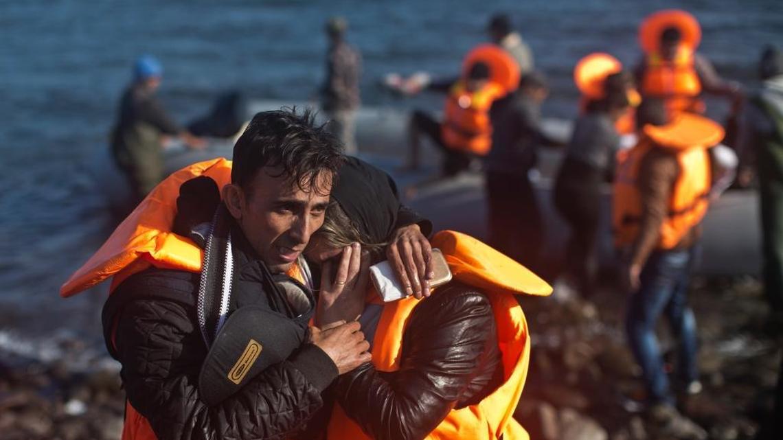A man hugs his spouse after travelling by boat to a beach on the northern shore of Lesbos, Greece, Saturday, Nov. 7, 2015.