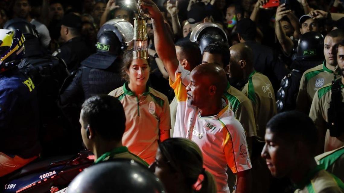 David Vieira Bisbo, a bar owner in the Chapeu Mangueria slum, holds the Olympic flame after his Olympic torch run along the streets of Copacabana, as the torch makes its way to the Opening Ceremonies of the 2016 Summer Olympics in Rio de Janeiro on Friday, Aug. 5, 2016.