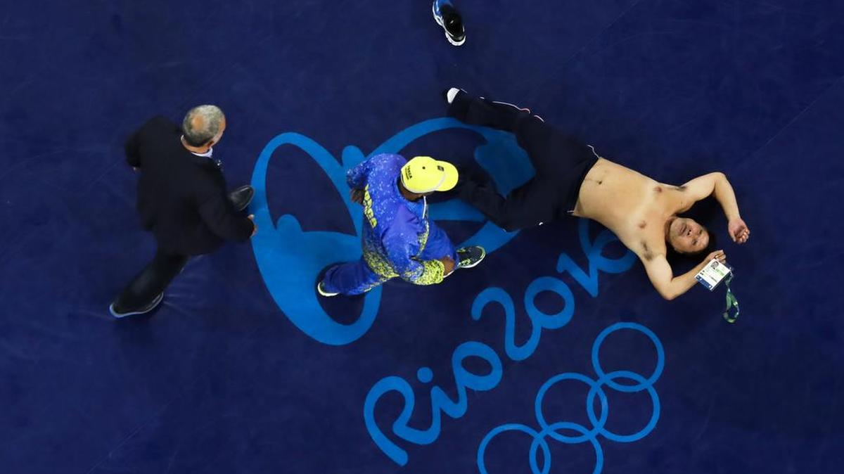 A coach of Mongolian wrestler Mandakhnaran Ganzorig takes off his clothes in protest of the decision of the jury to award the bronze medal to Uzbekistan’s Ikhtiyor Navruzov during the men’s 65-kg freestyle wrestling competition at the 2016 Summer Olympics in Rio de Janeiro, Brazil, Sunday, Aug. 21, 2016.