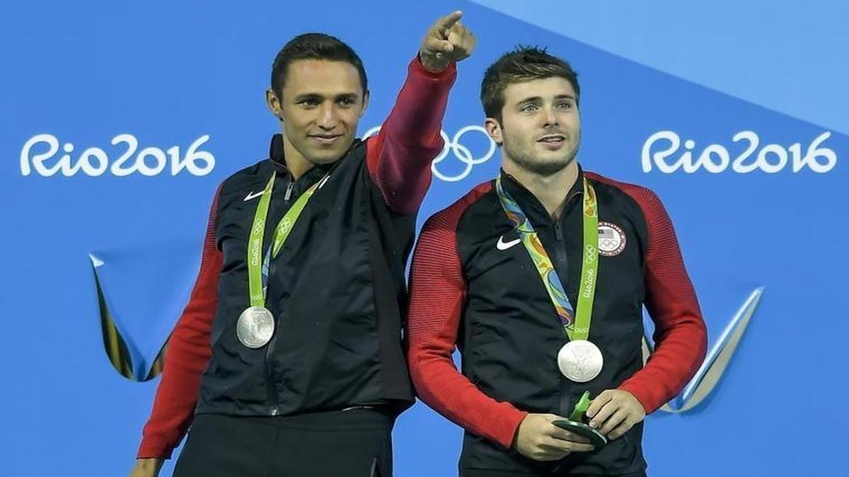 U.S. diver Sam Dorman, left, from the University of Miami, points to the crowd as he and Michael Hixon celebrate after winning the silver medal in the men’s 3-meter synchronized diving event at the Summer Olympics in Rio de Janeiro. Their clutch final dive brought them the medal.