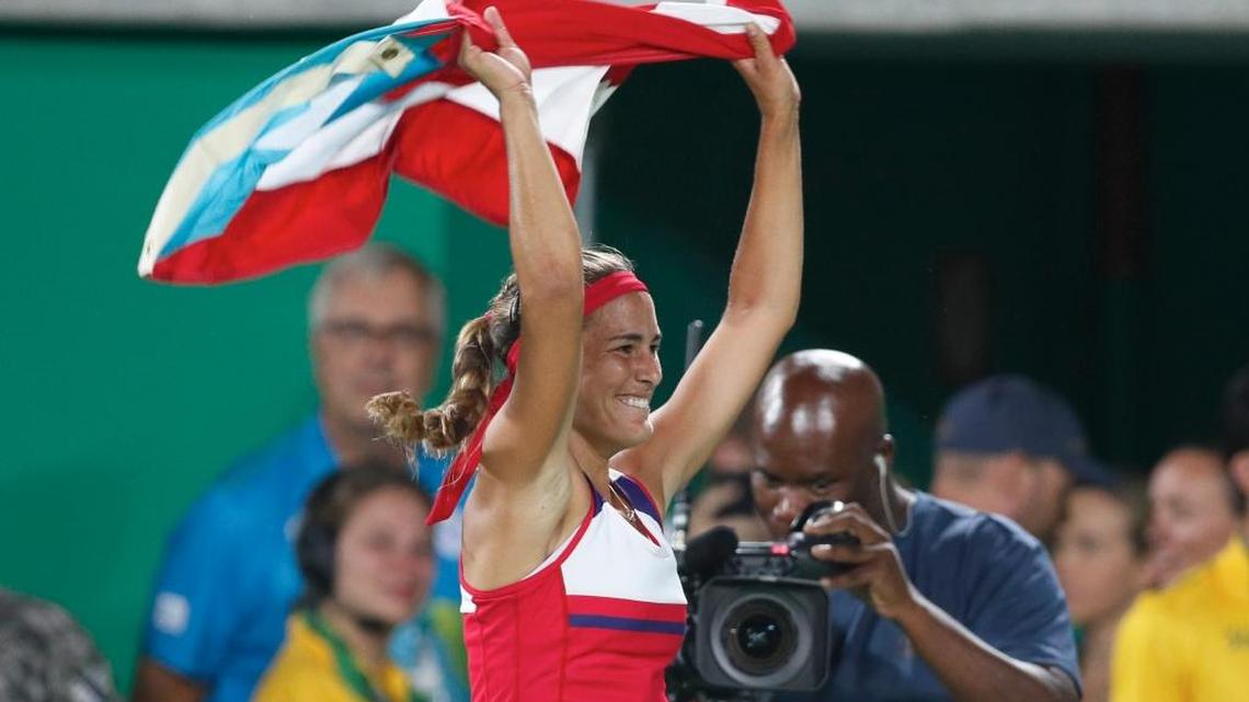 Monica Puig of Puerto Rico celebrates holding her country's flag after winning the gold medal match in the women's tennis competition at the 2016 Summer Olympics in Rio de Janeiro, Brazil, Saturday, Aug. 13, 2016.