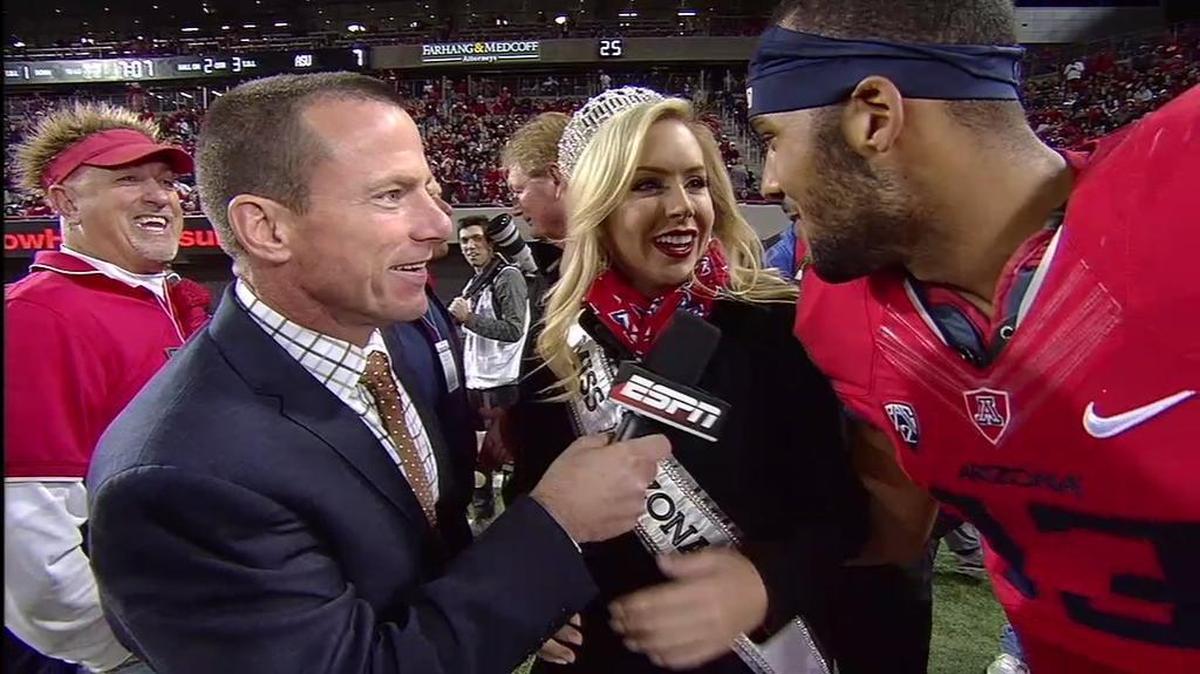 In this image taken from ESPN video, Arizona quarterback Brandon Dawkins apologizes to Miss Arizona USA, Tommy Lynn Calhoun, after he tackled her on the sideline during Friday’s game against Arizona State in Tucson.