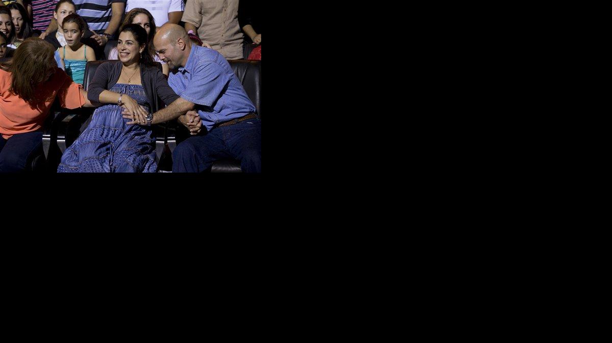 Gerardo Hernández, derecha, miembro del grupo de espías conocido como "Los Cinco", toca la panza de su esposa embarazada Adriana Pérez durante un concierto del cantante Silvio Rodríguez en La Habana, Cuba, el sábado 20 de diciembre de 2014.