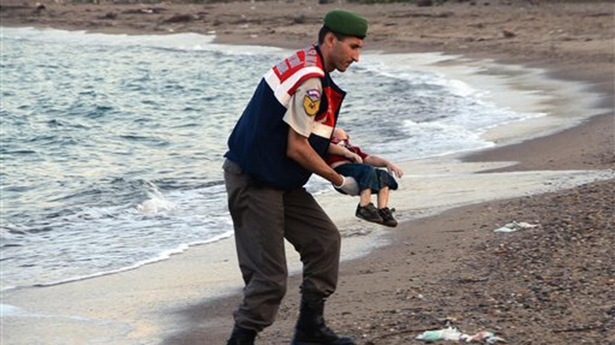 Un policía paramilitar transporta el cadáver de un niño migrante que apareció en las costas turcas cerca de Bodrum en la madrugada del 2 de septiembre del 2015.(AP Foto/DHA) TURKEY OUT